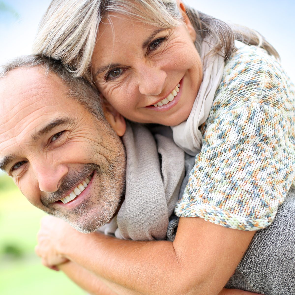 A woman hugging her husband from behind, both smiling