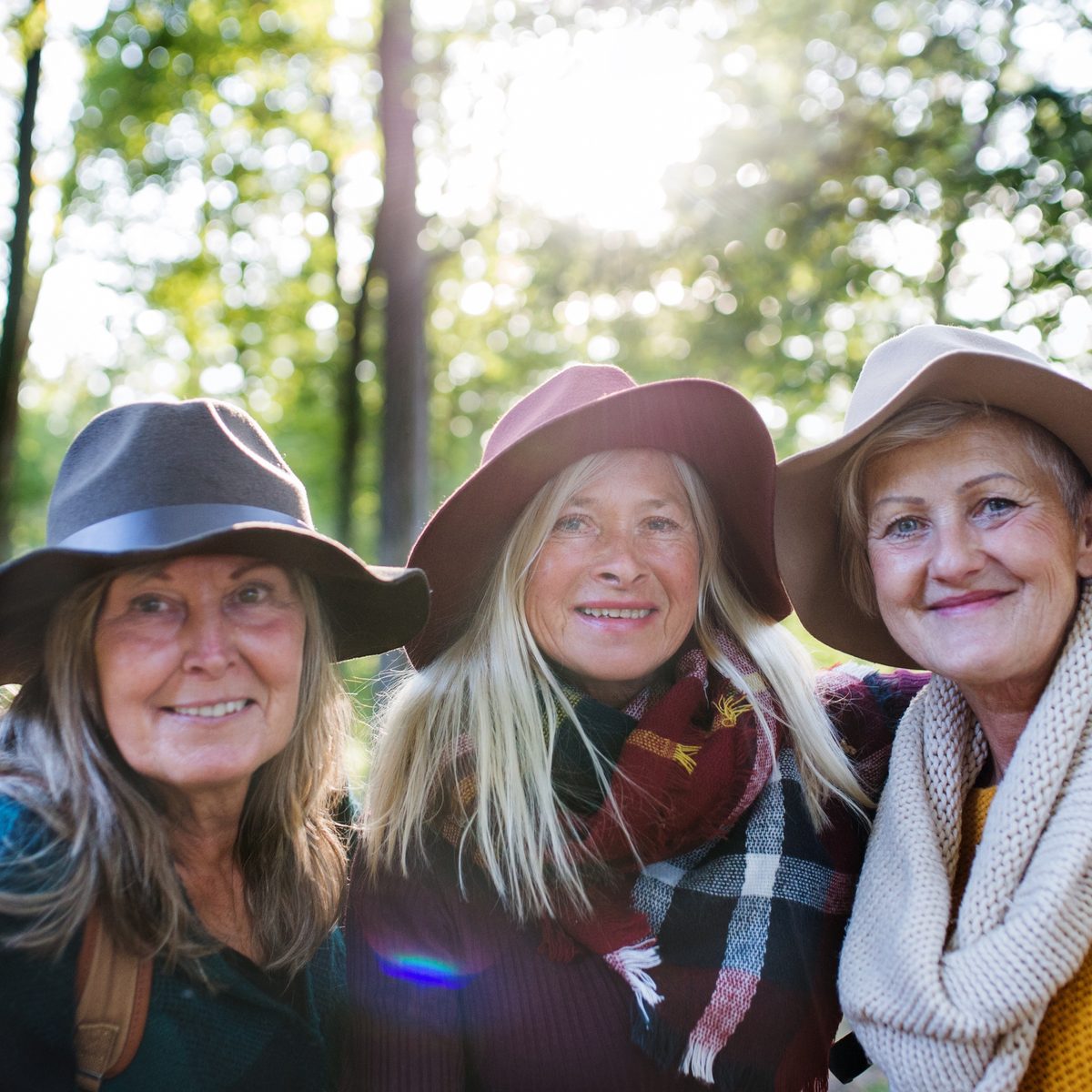 Three friends in sun hats on a walk through the woods